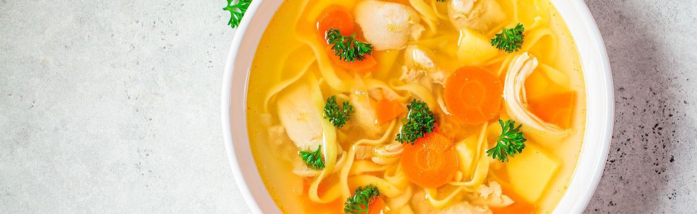 Caldo de pollo con zanahorias, verduras, hierbas de olor y pollo con calidad Avigrupo servido en la mesa