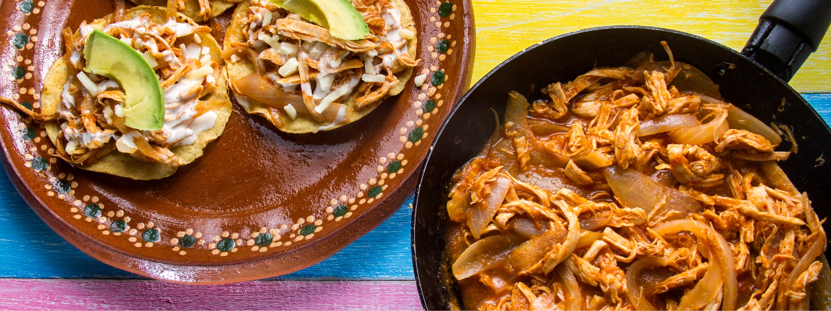 Tostadas de tinga de pollo con topping de crema y rebanadas de aguacate